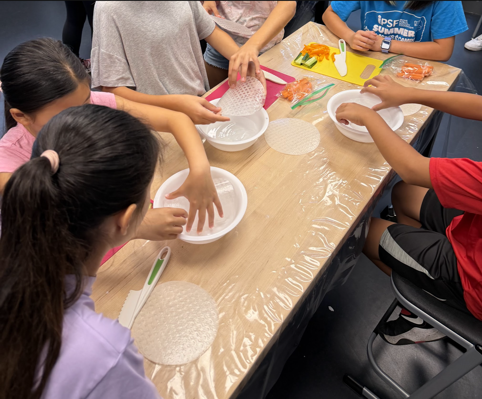 Students soak rice paper wrappers — a key step in making fresh spring rolls