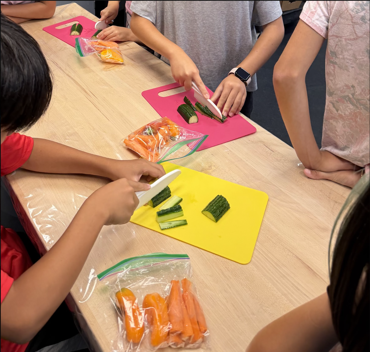 Students practice knife skills, cutting cucumbers and carrots for their spring rolls